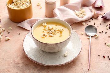 Bowl with tasty popcorn soup on color background