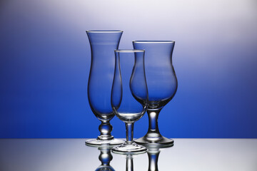 Empty glasses on color background