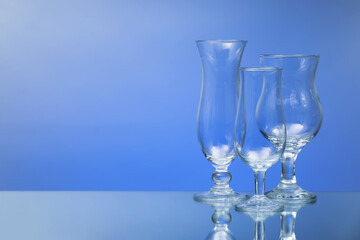 Empty glasses on color background