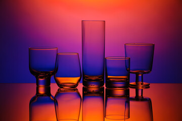Empty glasses on color background