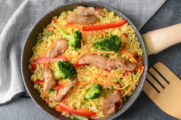 Frying pan with tasty rice on dark background