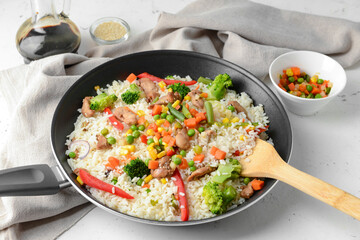 Frying pan with tasty rice on table