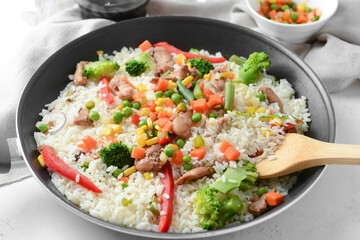 Frying pan with tasty rice on table