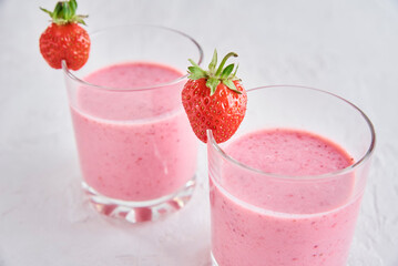 Two glasses with strawberry shake on white background