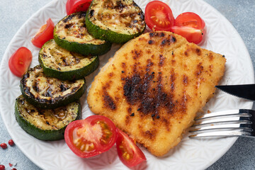 Schnitzel of chicken and zucchini cooked on the grill. Fresh tomatoes on a plate. Ready delicious dinner lunch.