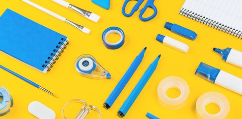 Assorted office and school white and blue stationery on bright yellow background. Organized knolling for back to school or education and craft concept. Selective focus. Filled frame Banner