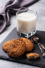 Homemade cookies cereals oats and a glass of milk on the grey concrete table. Copy space.
