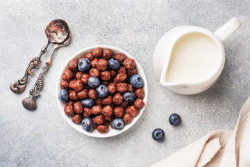 Chocolate flakes made from natural cereals with fresh blueberries, honey and milk. The concept of a healthy wholesome Breakfast. copy space Grey concrete background