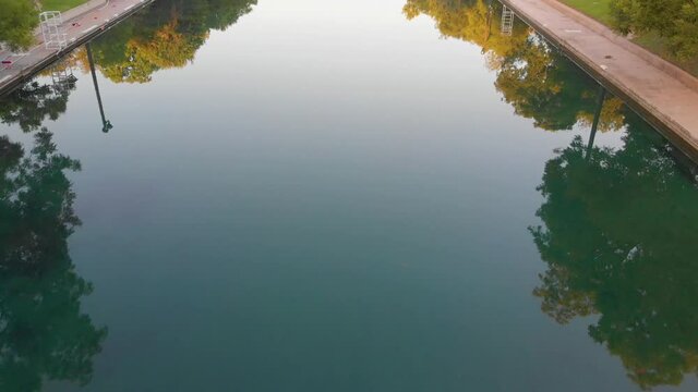 Top down shot of the crystal clear waters of barton springs pool. Slow pan up to downtown Austin Texas.