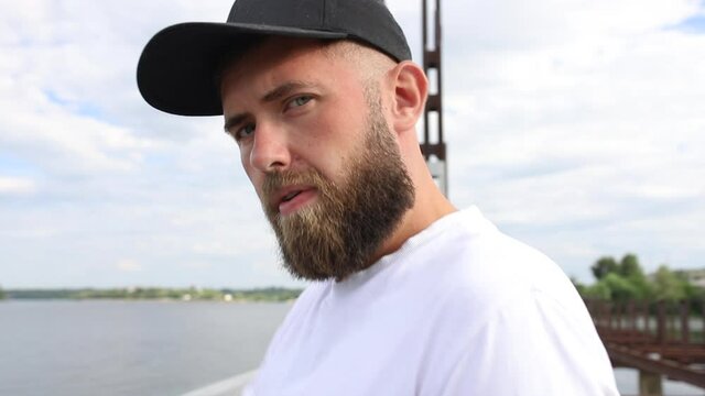 The guy looks at the camera and puts on a cap