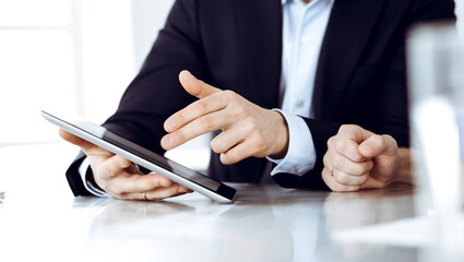 Business people using tablet computer while working together at the desk in modern office. Unknown businessman or male entrepreneur with colleague at workplace. Teamwork and partnership concept