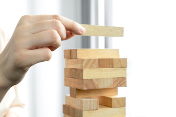 Hands of businesswomen playing wooden block game. Concept Risk of management and strategy plans for business growth and success