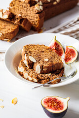Portion of nut-fruit bread with yogurt and figs. Vegan banana bread, white background.