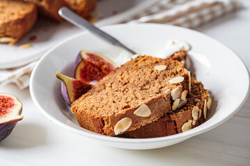 Fototapeta na wymiar Portion of nut-fruit bread with yogurt and figs. Vegan banana bread, white background.