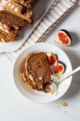 Portion of nut-fruit bread with yogurt and figs. Vegan banana bread, white background.