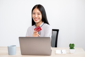 The Asian businesswoman's hand is holding a credit card and using a laptop for online shopping and internet payment in the office