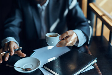 Fototapeta na wymiar Business man in a cafe documents a cup of coffee on the table official work