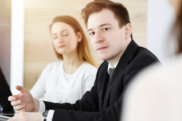 Businessman headshot at meeting in sunny office. Unknown entrepreneur sitting with colleagues at the background