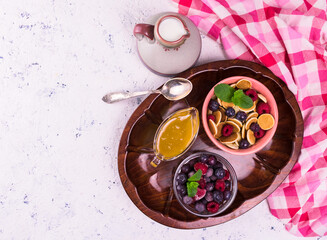 Breakfast of mini pancakes with berries and honey on a tray. Copy space. Flat lay.