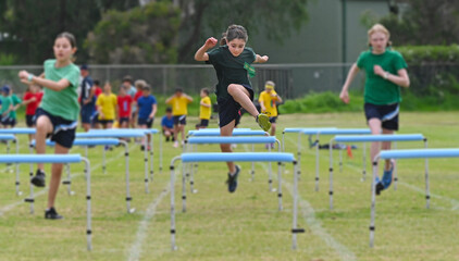 Young girl runs a hurdle