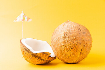 Happy coconuts day concept, fresh coconut and sun umbrella, studio shot isolated on yellow background, Beach tropical fruit spring summer holiday