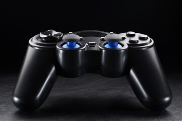 Black wireless gamepad or joystick on black background.