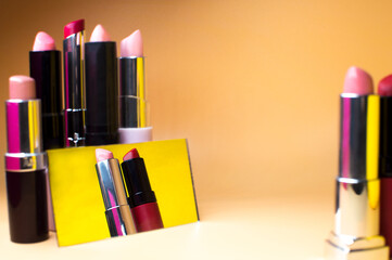 Different lipsticks next to the mirror. The lipsticks are reflected in the mirror. Bright collection with a copy space