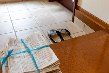古い新聞紙の束と玄関のスリッパ