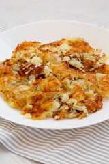 Homemade Fried Hashbrowns on a white plate, side view.