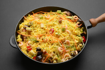 Frying pan with tasty rice on dark background