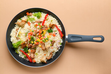 Frying pan with tasty rice on color background