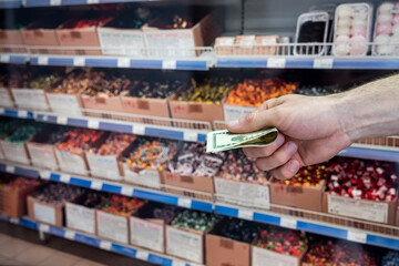 man holds dollars in the supermarket