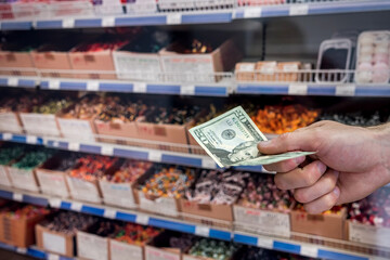 man holds dollars in the supermarket