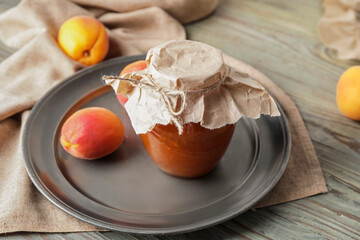Jar of tasty apricot jam on table