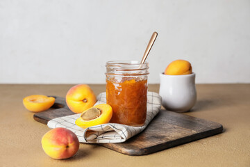 Jar of tasty apricot jam on table