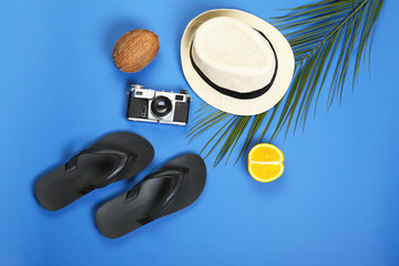 Male flip-flops with hat and photo camera on color background