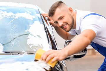 Male worker washing car outdoors