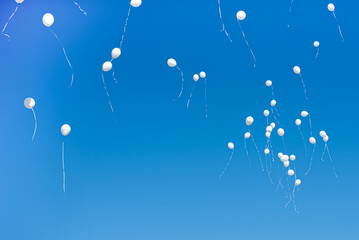 White balloons flying in the blue sky