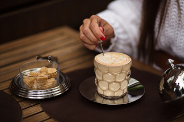 Women's hand made cup of coffee and brown cane sugar. Sitting in a cafe. Close-up