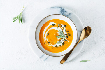 Carrot and ginger cream soup with pumpkin seed and fresh herbs. Selective focus.