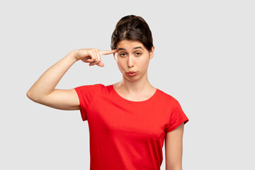 Stupid gesture. Crazy idea. Woman showing cuckoo sign. Looking at camera isolated on neutral copy...