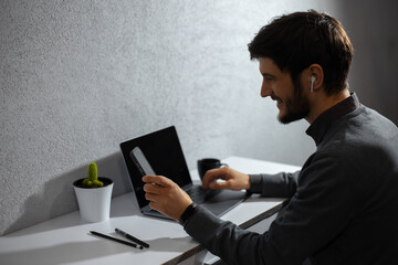 Portrait of young businessman, using smartphone, laptop and other supplies for office work.