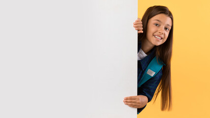 Girl hiding behind blank white advertising signboard