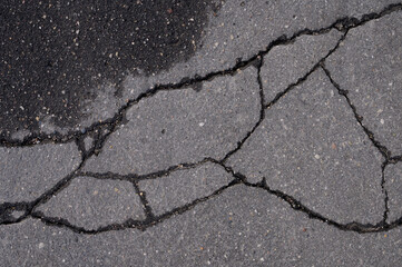 Abstract background of old cracked asphalt with wet traces of cars
