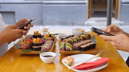 Two people browsing on their phones during their sushi lunch avoiding real communication....