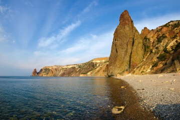 Coastal cliffs and pebble beach on sea against the sky