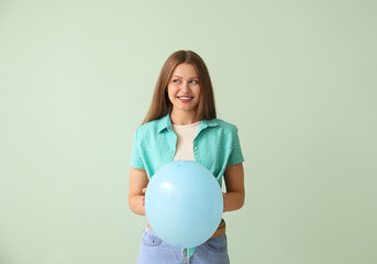 Young woman with balloon on color background