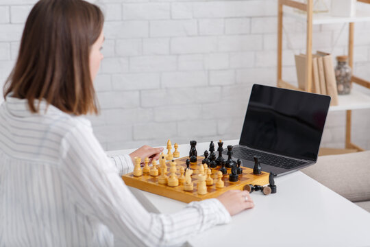 Online teacher during self-isolation. Girl watches video lesson and play in chess