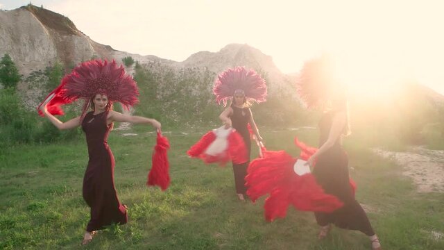 Women in red carnival costumes dance in the sunlights in nature