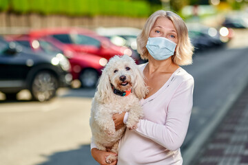 Portrait elderly woman with a dog outdoors an antivirus mask